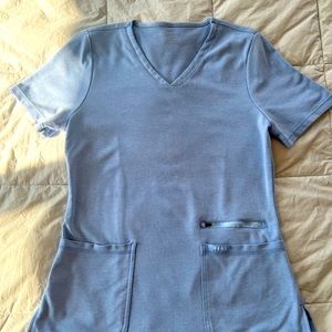 Jaanuu 4 pocket v neck scrub top in Spinryx fabric. Color is ceil blue.